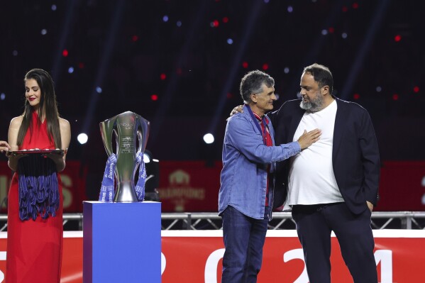 Olympiakos head coach José Luis Mendilibar, second from right, acknowledges club owner Evangelos Marinakis, right, after winning the Greek Super League championship for the 2024-2025 period at Georgios Karaiskakis Stadium in Piraeus port city of Athens, Greece, Sunday, May 4, 2025. (AP Photo/Yorgos Karahalis)